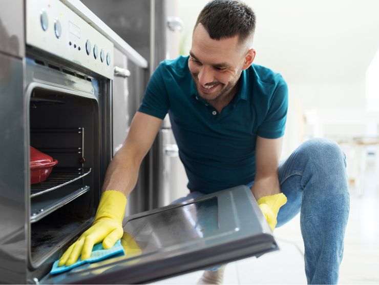 uomo sorridente che pulisce forno