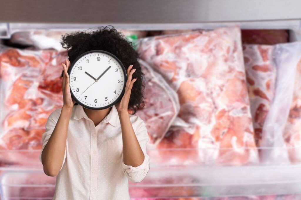 sacchetti di carne nel freezer e donna che mantiene in mano un orologio