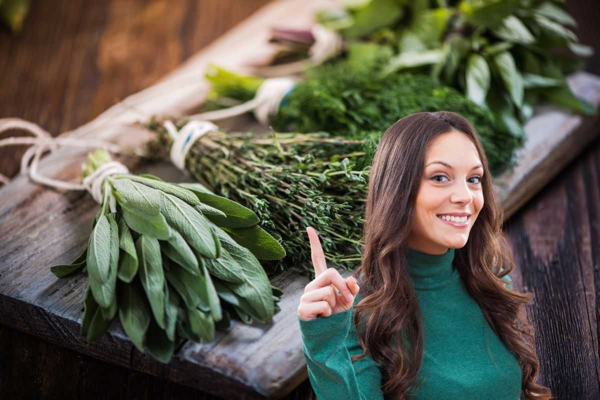 donna sorridente che indica erbe aromatiche su un vassoio