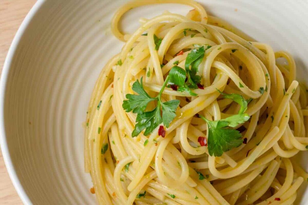 spaghetti aglio ed olio con prezzemolo in un piatto bianco