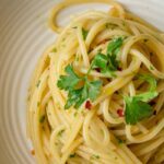 spaghetti aglio ed olio con prezzemolo in un piatto bianco